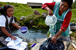 A mother and daughter, lacking water at home, wash clothes in a nearby spring. Photo: Rodrigo Cruz/Wall Street Journal
