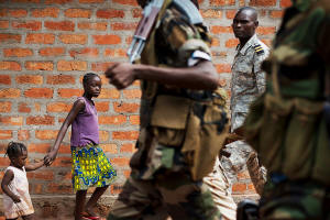Children walking along the street while two members of a CAR rebel group walk by with guns. Photo: Jacob Zocherman/New York Times with