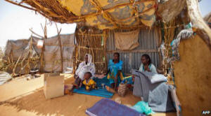 Photo of four refugees from fighting in Darfur in a makeshift hut.