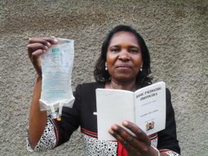 Prof Grace Irimu shows IPS a drip feed bag and a copy of Kenya�s �Basic Paediatric Protocols� as she explains the importance of intravenous treatment in saving the lives of young children affected by acute watery diarrhoea. Credit: Miriam Gathigah/IPS