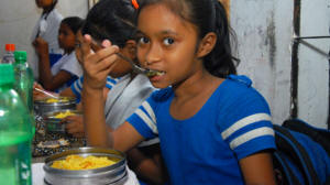 A young girl eats a fortified lunch through the school nutrition program. Photo: GAIN