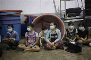 In this Monday, Nov. 9, 2015 photo, children and teenagers sit together to be registered by officials during a raid on a shrimp shed in Samut Sakhon, Thailand. Photo: AP Photo/Dita Alangkara