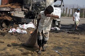 A Yemeni drags a sack away from a truck that was allegedly destroyed by an airstrike of the Saudi-led coalition targeting a wheat convoy. Photo: Abdul-Rahman Hwais/EPA